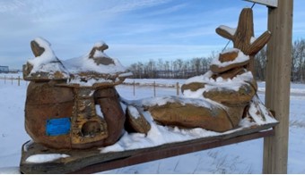 “Wrangler’s Rest” reclining cowboy, chainsaw sculpture  